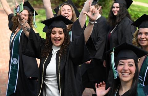 Group of students in cap and gown celebrate commencement