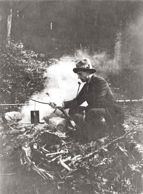 man cooking at a camp fire in 1912