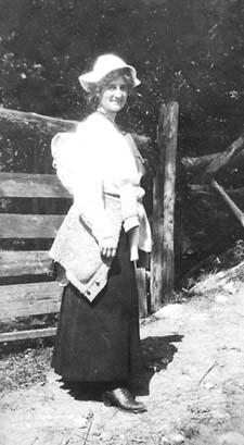 Young woman standing at the main trailhead across from the Ravine House.