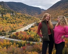 Two women pose in front of scenic road.