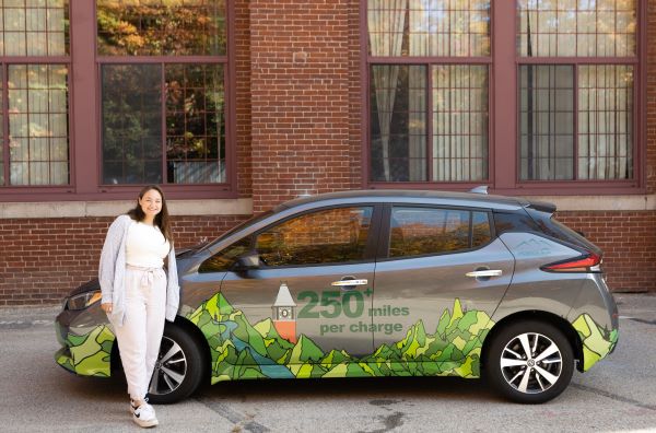 Student in front of electric vehicle