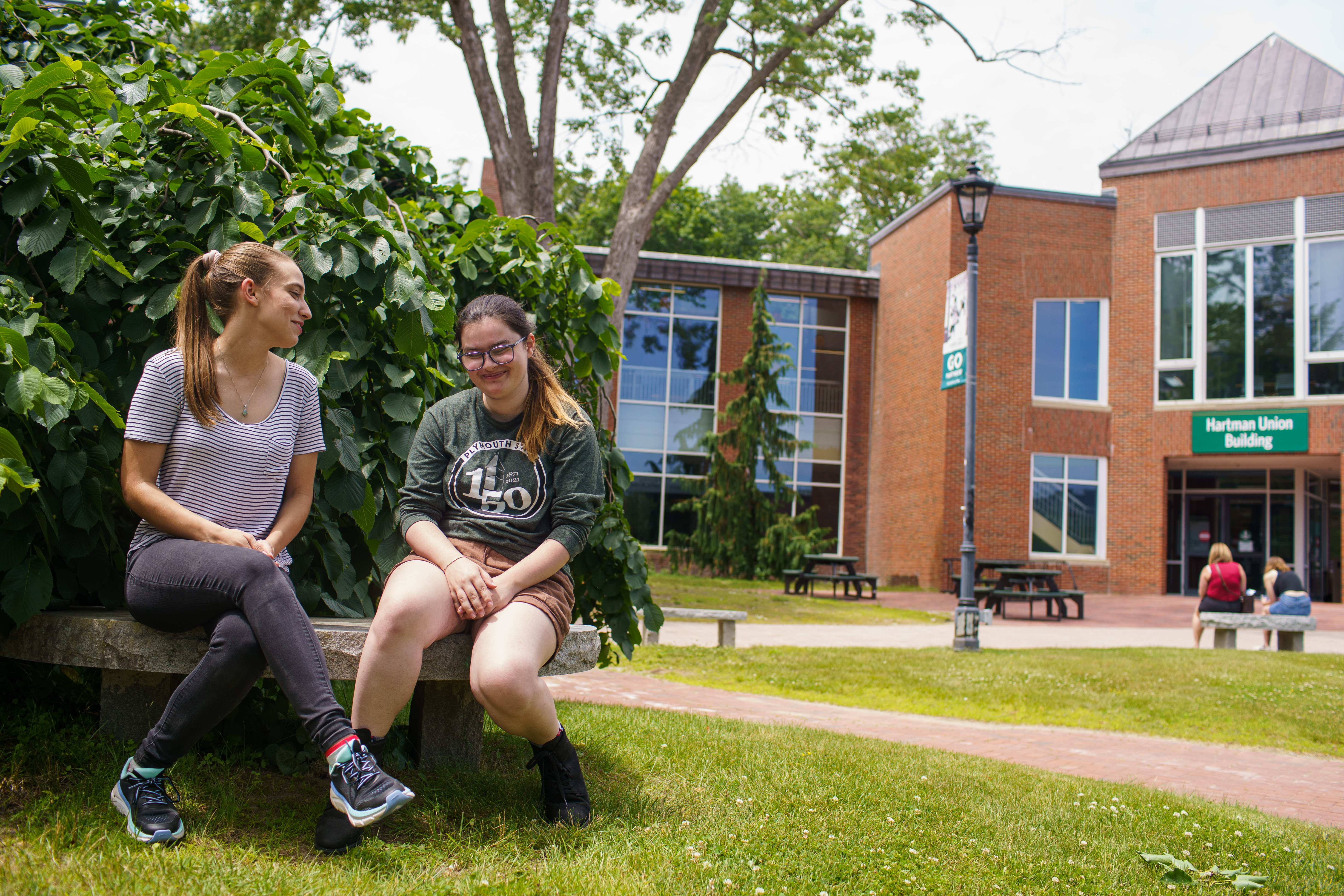 Two students talking on a bench outside of Hartman Union Building