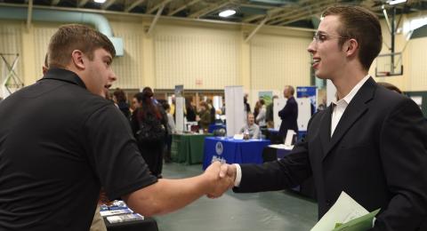 Student shaking hands at career fair.