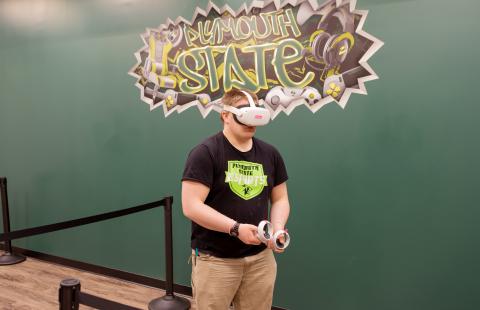 A male student uses a Virtual Reality headset in Plymouth State University's eSports lounge