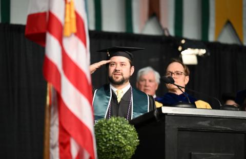 Image of graduate saluting at homecoming