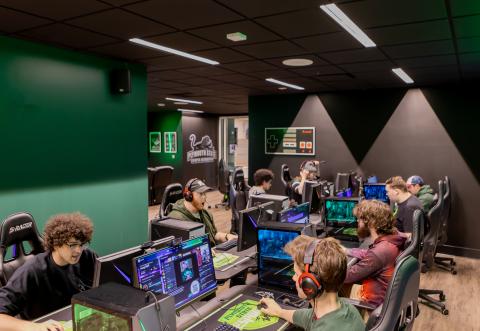 8 students sit at an 8-person gaming station in the PSU eSports lounge.