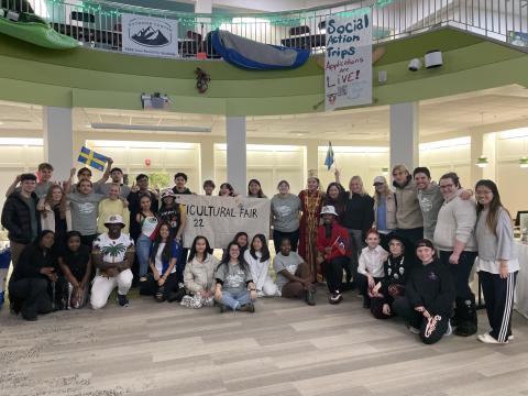 Students stand in a semi-circle at the Multicultural Fair dressed in clothing representative of their identities and backgrounds.
