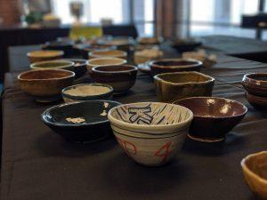 Pottery bowls sit empty on a table of varying colors.