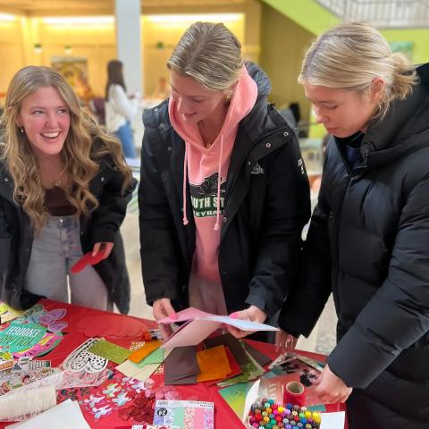 Three students make crafts and laugh together.