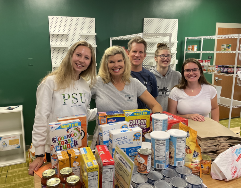Group of people together in front of canned food items.