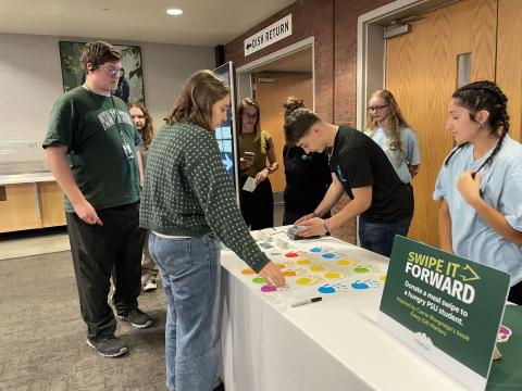 Student interacting with individuals at a desk.