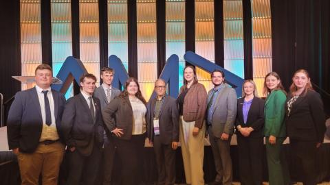 Ten individuals dressed in business attire stand side by side, posing for a photo.