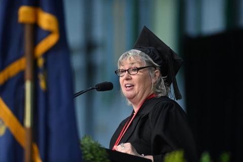 Commencement speaker, Tina Schumacher, looks into the croud, speaking into a microphone.